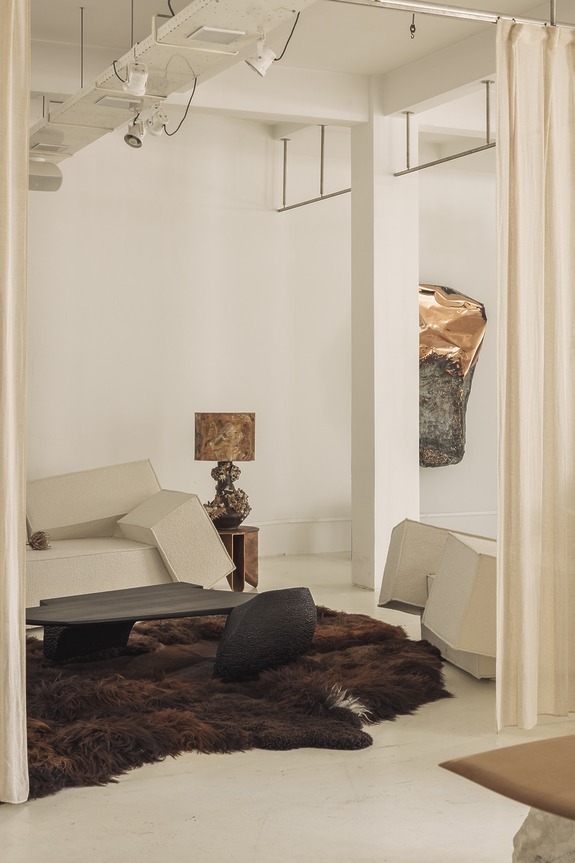 Minimalistic living room with modern white furniture, a unique lamp, a brown textured rug, and abstract wall art.