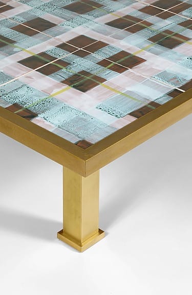Modern coffee table with a colorful grid pattern on top and gold legs.