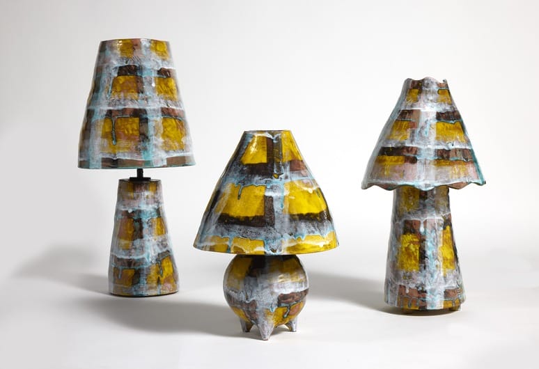 Three abstract, colorful ceramic lamps of varying shapes displayed on a white background.