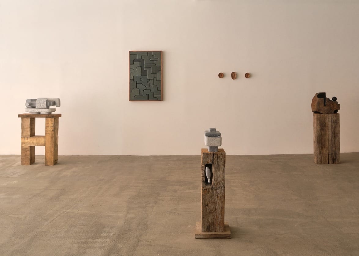 Modern art gallery with abstract sculptures and paintings on a minimalist, neutral-toned floor and walls.