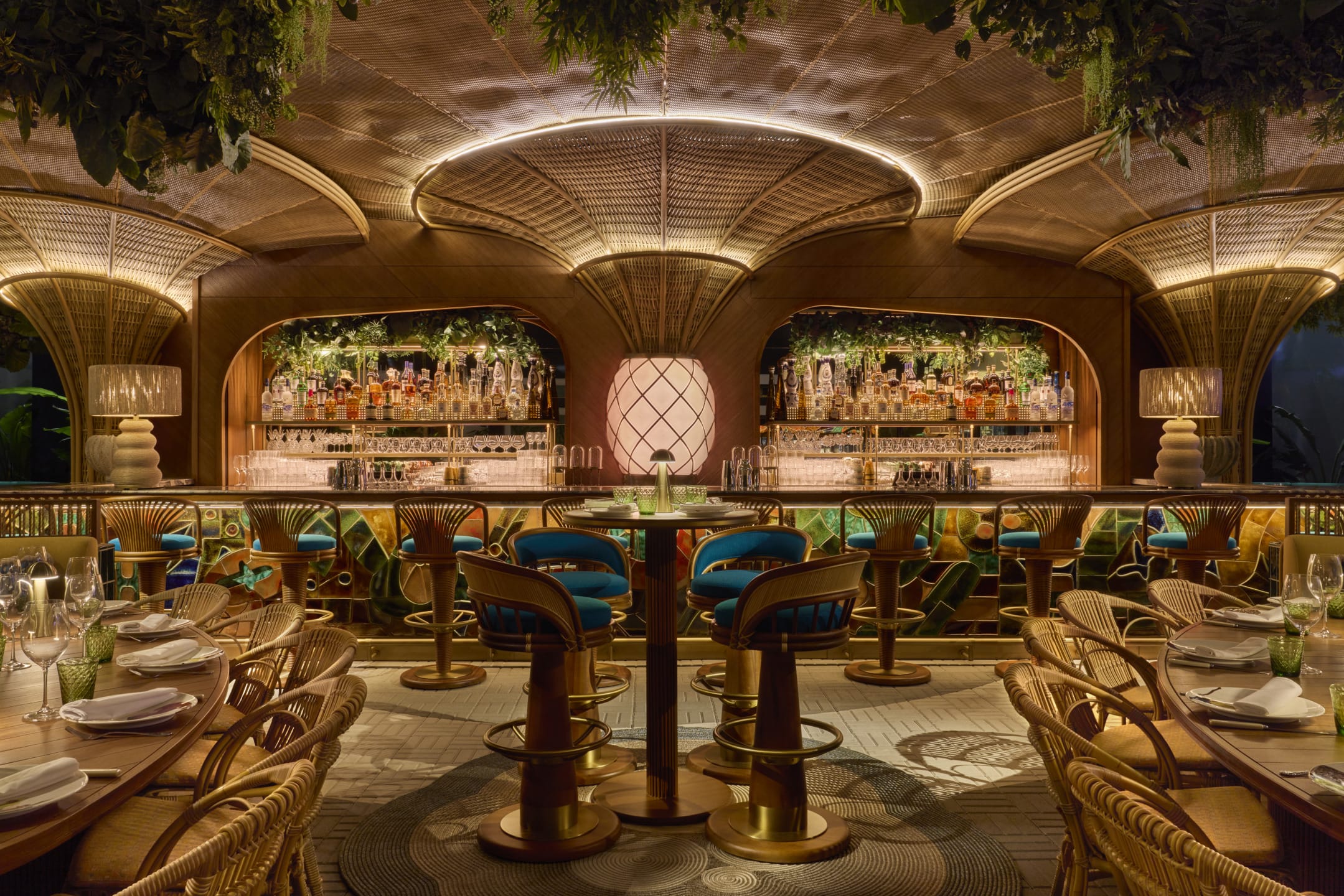Chic restaurant interior with elegant wooden decor, ambient lighting, and a fully stocked bar in the background.