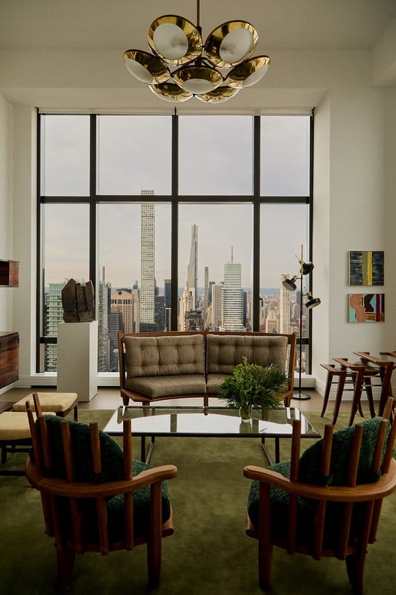 Loft apartment interior with modern furniture and large windows offering a view of a city skyline.