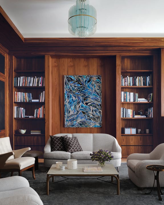 Elegant living room with wooden bookshelves, abstract painting, and modern furniture.