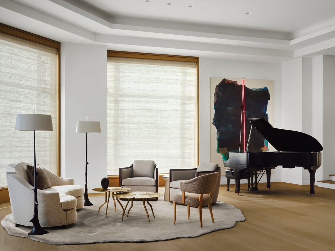 Modern living room with a grand piano, floor lamps, beige armchairs, and a large abstract painting on the wall.