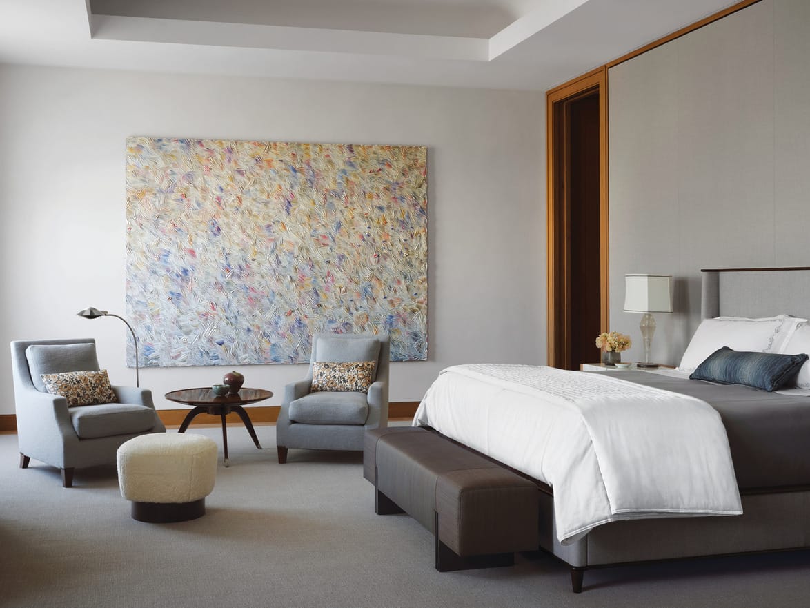 Modern hotel room with a large abstract painting, king-sized bed, seating area, and contemporary decor.