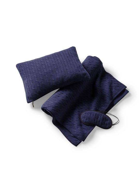 Navy blue travel set with pillow, blanket, and eye mask featuring a textured pattern on a white background.