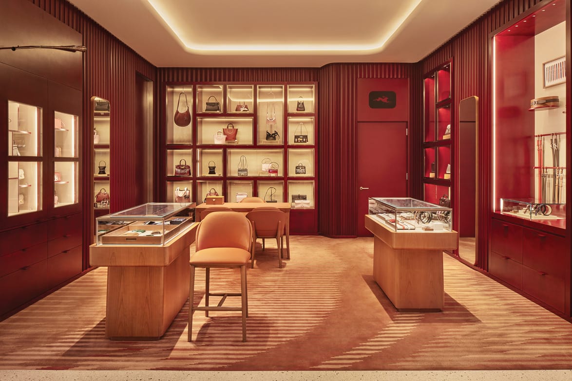 Luxurious boutique interior with warm lighting, showcasing handbags, accessories, and display cases on elegant wooden furniture.