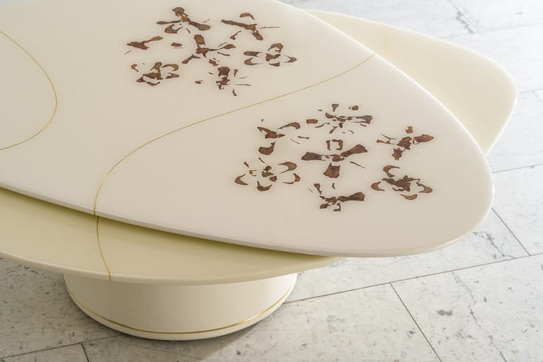 Close-up of surfboard tails with intricate brown floral artwork on a cream background, resting on a speckled concrete floor.