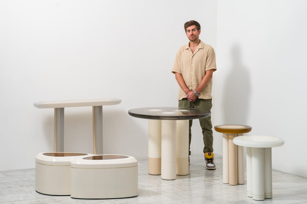 Man standing beside modern minimalist furniture display in a bright showroom.