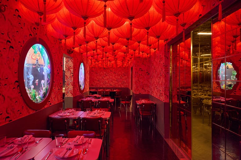 Vibrant restaurant interior with red lanterns and round windows, reflecting a colorful and immersive dining experience.