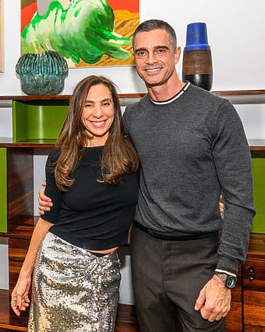 Smiling couple standing together in a stylish room with shelves and decorative items in the background.