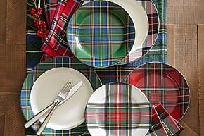 Plaid-patterned plates and napkins arranged on a table with silverware and festive decor.
