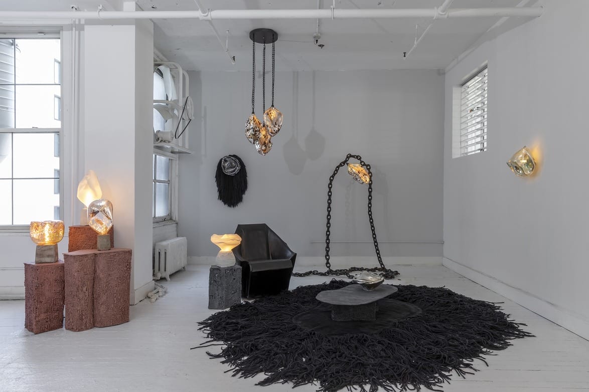 A modern art gallery interior with unique sculptures, a black rug, and contemporary lighting fixtures.