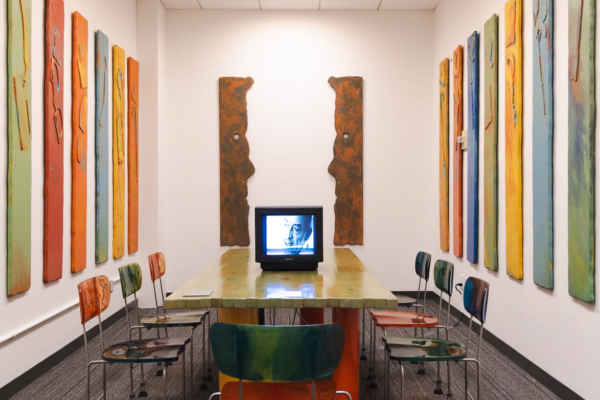 Conference room with colorful art, table, chairs, and an old TV displaying black-and-white footage.