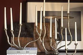 Silver candelabras with white candles on a shelf, decorative artwork in the background.