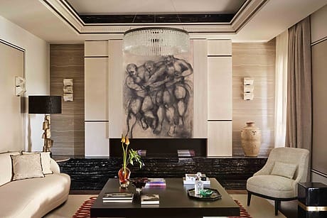 Elegant living room with modern art, large chandelier, stylish furniture, and decorative rug in warm neutral tones.