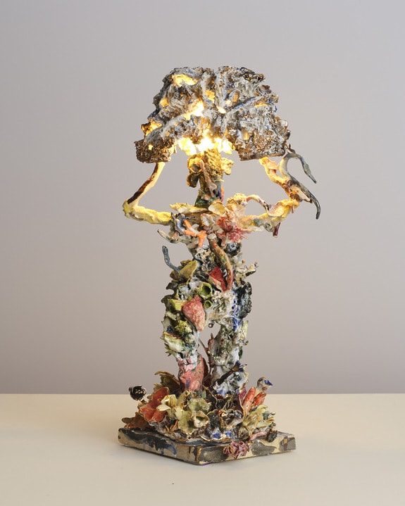 Abstract sculpture lamp with organic shapes and vibrant colors, resembling a human form supporting a tree-like light fixture.