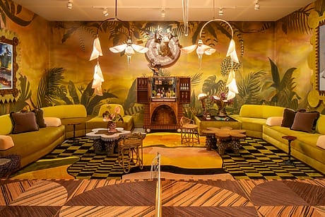 Vibrant tropical-themed room with yellow sofas, abstract lighting, and a decorative cabinet at the center.