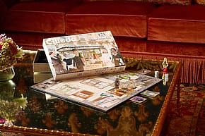 Cluedo board game setup on a glass table with dice and detective figures.