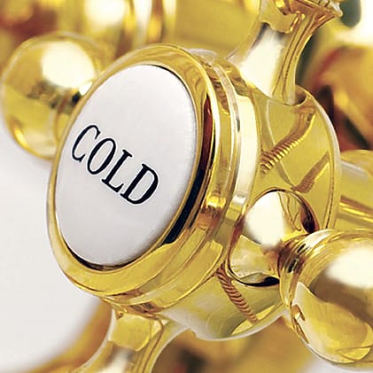 Close-up of a golden faucet handle labeled "COLD" with intricate design details.