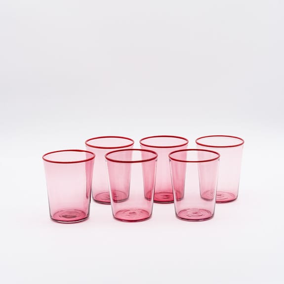 Six pink transparent drinking glasses arranged in two rows on a white background.
