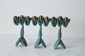Artistic blue and gold candle holders shaped like tulip flowers on a light surface, against a plain white background.