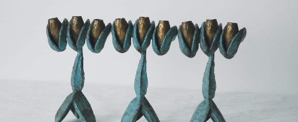 Artistic blue and gold candle holders shaped like tulip flowers on a light surface, against a plain white background.