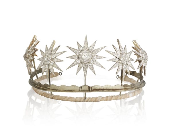 A diamond tiara featuring star-shaped gemstone designs on a simple metal band.