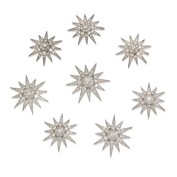 Eight vintage starburst brooches with sparkling rhinestones arranged in a scattered pattern on a white background.