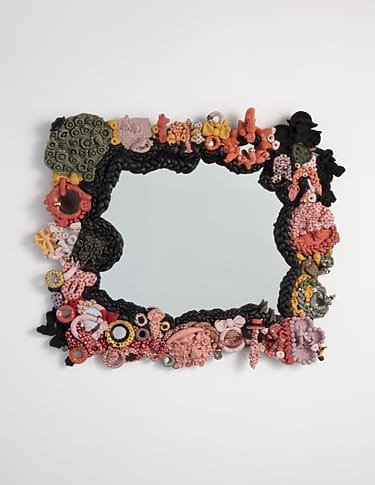 Colorful, intricately designed mirror frame with various abstract shapes and textures against a white background.