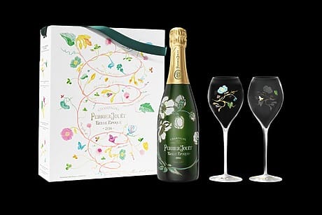 Champagne bottle with floral design box and two elegant wine glasses on a black background