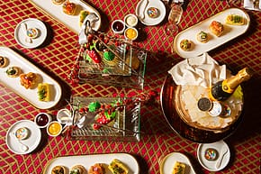 Assorted gourmet dishes and champagne on a festive red tablecloth, arranged in an elegant dining setting.
