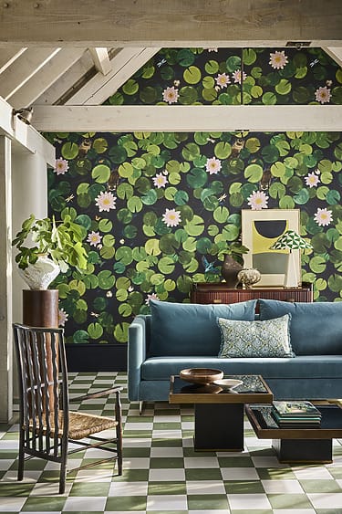 Cozy living room with green floral wallpaper, blue sofa, patterned tiles, and decorative plants and furniture.