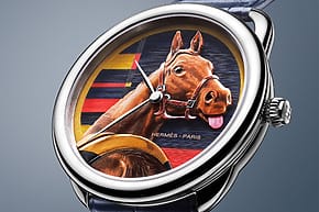 Close-up of a luxury wristwatch with a detailed equestrian design on the face, featuring a vivid horse illustration.