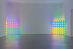 Colorful neon light installations on facing walls in a modern gallery space, creating a vibrant and colorful atmosphere.