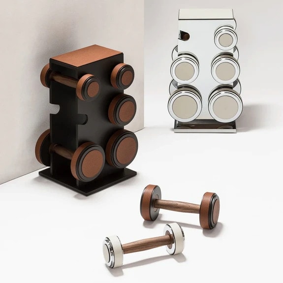 Set of modern dumbbells and matching stands with sleek design placed on a minimalist floor setting.