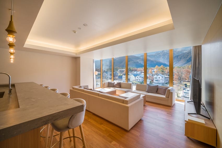 Modern living room with large windows, mountain view, cozy seating area, and stylish bar counter with pendant lights.