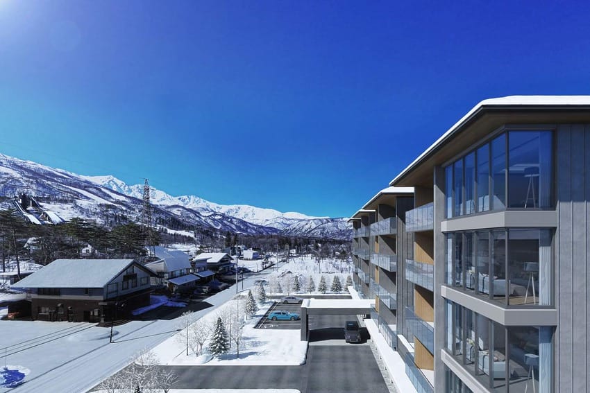 Modern building with large windows set against a snowy mountain backdrop under a clear blue sky.