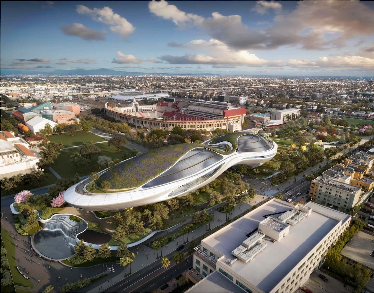 Aerial view of a futuristic museum with curved architecture surrounded by greenery and cityscape in the background.
