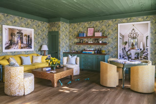 Eclectic living room with yellow sofa, patterned wallpaper, green cabinets, and colorful decorations.