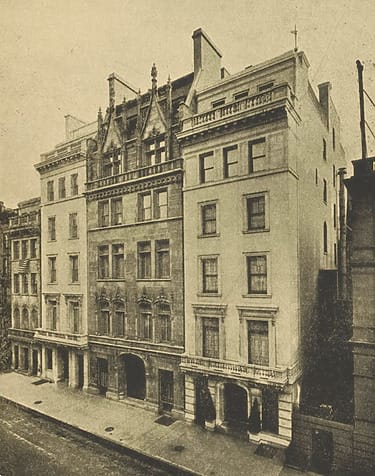 Vintage photo of a row of historic urban buildings with ornate architectural details along a city street.