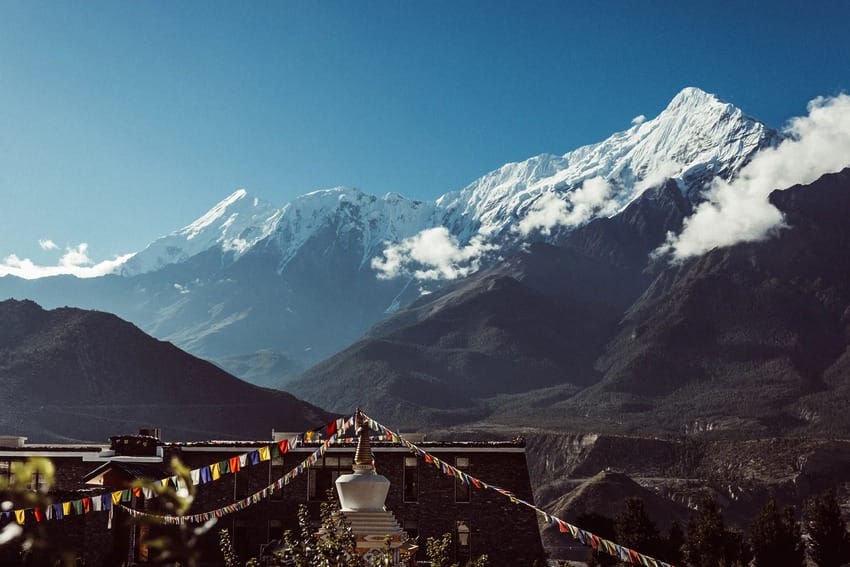 snow-capped mountains with prayer flags in the foreground under a clear blue sky