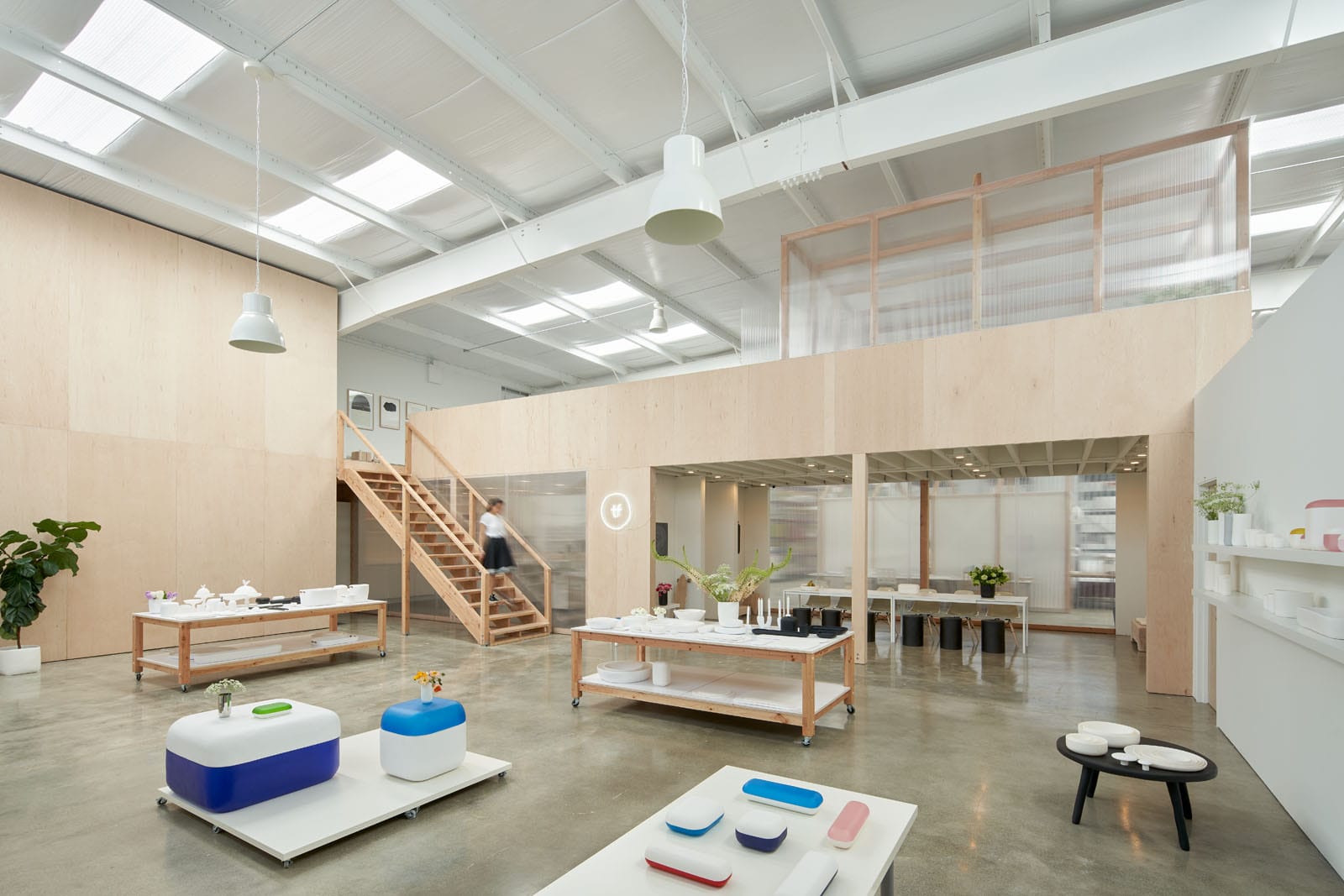 Modern open-concept interior with wooden accents, minimalist furniture, and large windows, showcasing studio and workspace.