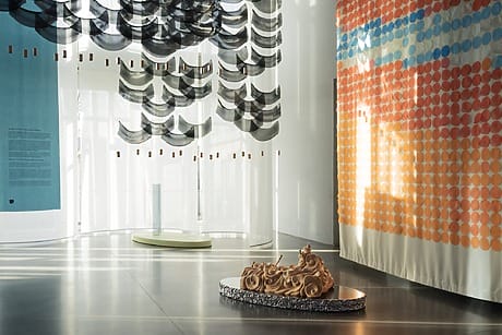 Modern art installation featuring abstract sculptures and colorful patterns in a spacious gallery with natural light.