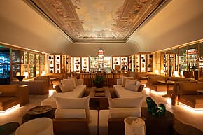 Luxurious hotel lobby with elegant sofas, ambient lighting, and intricate ceiling artwork, creating a warm and inviting atmosphere.