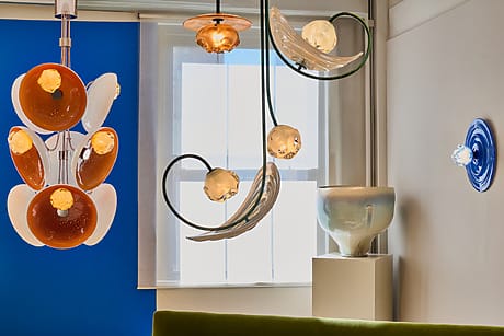 Modern lighting fixtures in a bright room with colorful ceramic art pieces and a large window in the background.