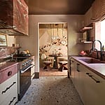 Stylish kitchen with red marble countertops, modern appliances, and a view into a chic dining area with artistic decor.