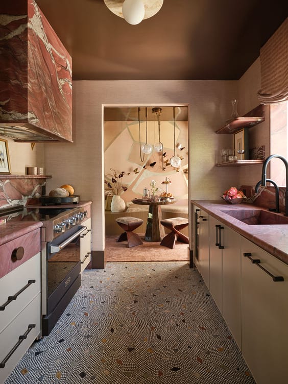 Stylish kitchen with red marble countertops, modern appliances, and a view into a chic dining area with artistic decor.