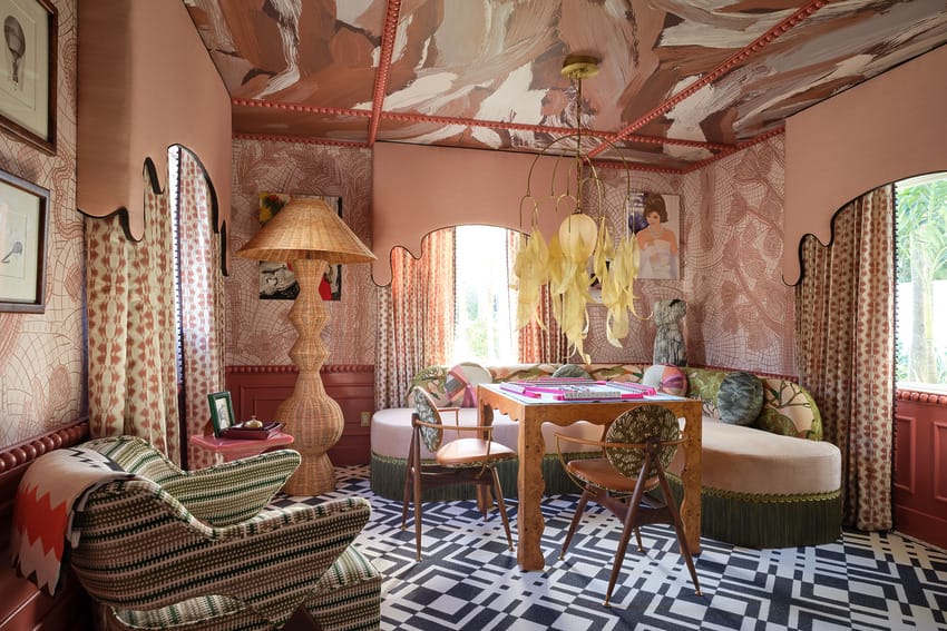 Eclectic room with patterned walls, unique chandelier, colorful furniture, and geometric black-and-white floor design.