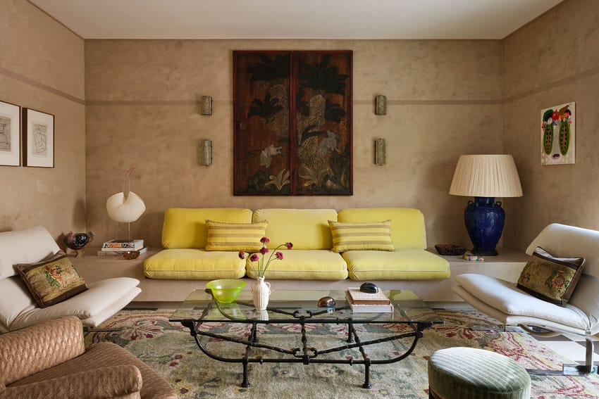 Elegant living room with yellow sofa, glass coffee table, and decorative rug, featuring wall art and stylish lighting.